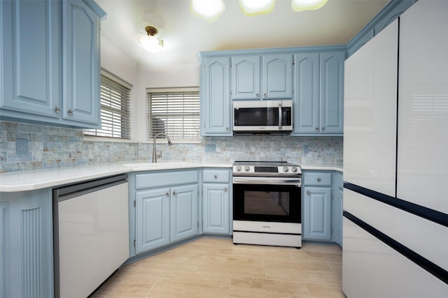 kitchen with stainless steel appliances, blue cabinetry, a sink, and light countertops