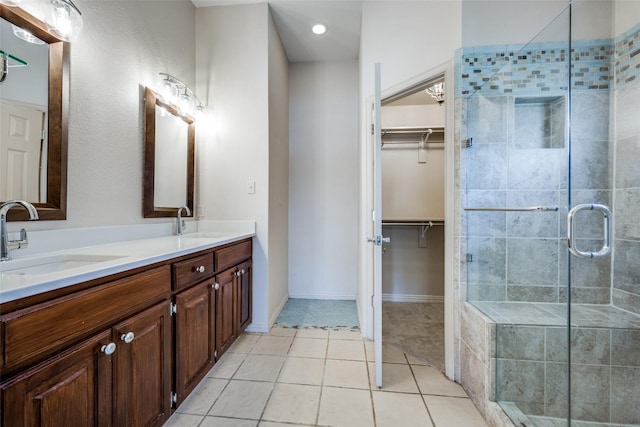 bathroom featuring tile patterned flooring, a sink, a walk in closet, and a shower stall