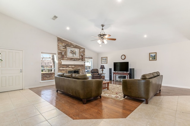 living room featuring visible vents, baseboards, a ceiling fan, tile patterned flooring, and a brick fireplace