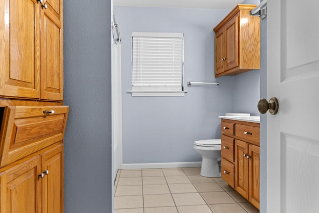 bathroom featuring tile patterned floors, toilet, vanity, baseboards, and walk in shower