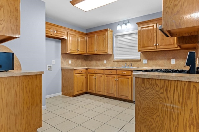 kitchen with brown cabinetry, light countertops, a sink, and backsplash