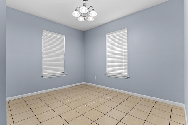 unfurnished room featuring a notable chandelier and baseboards