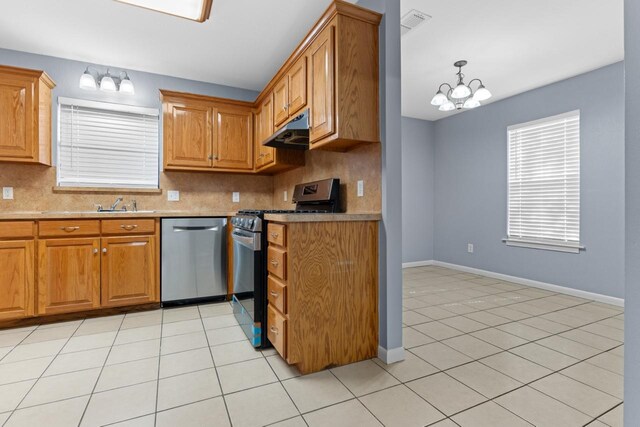 kitchen with light tile patterned floors, under cabinet range hood, stainless steel appliances, visible vents, and backsplash