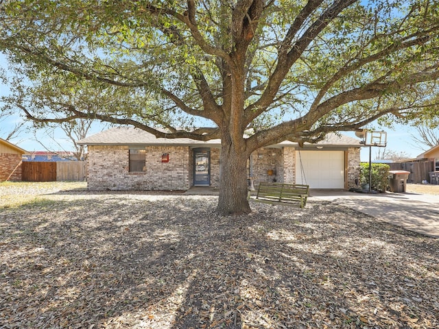 single story home with concrete driveway, brick siding, an attached garage, and fence