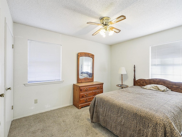 bedroom featuring light carpet, ceiling fan, a textured ceiling, and baseboards