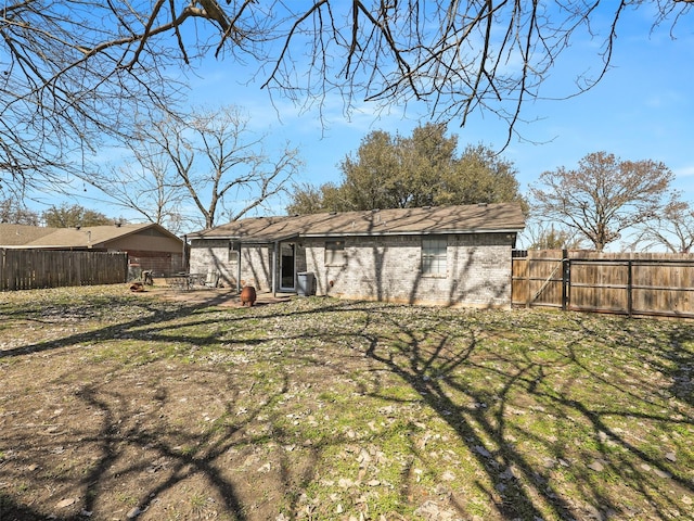 back of house featuring fence and brick siding