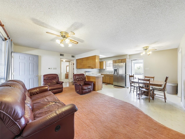 living area with a ceiling fan, visible vents, and a textured ceiling