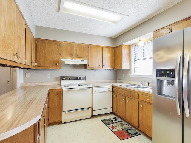 kitchen featuring white appliances, brown cabinetry, light floors, under cabinet range hood, and a sink