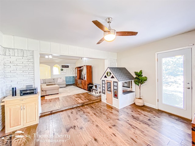 living area featuring light wood-style floors, baseboards, and a ceiling fan