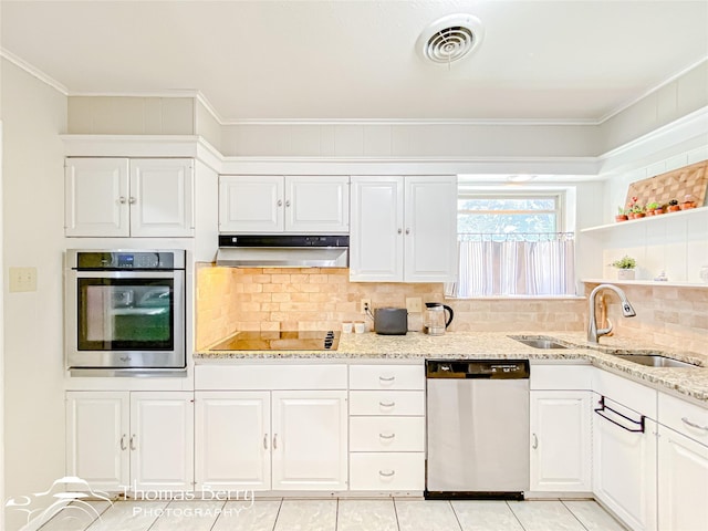 kitchen featuring under cabinet range hood, stainless steel appliances, a sink, visible vents, and backsplash