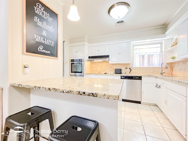 kitchen with under cabinet range hood, appliances with stainless steel finishes, white cabinets, and a sink