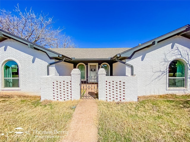 property entrance featuring brick siding and a shingled roof