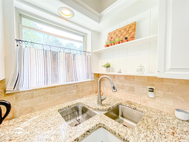 kitchen featuring open shelves, backsplash, a sink, and light stone countertops