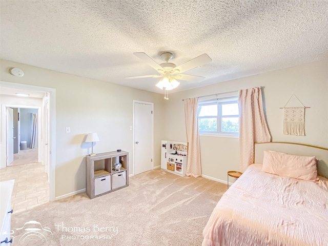 bedroom featuring light carpet, ceiling fan, a textured ceiling, and baseboards