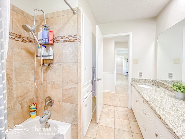 full bathroom with tile patterned flooring, tiled shower / bath, a textured ceiling, and vanity