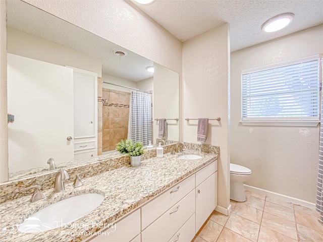 bathroom with toilet, a textured ceiling, baseboards, and a sink