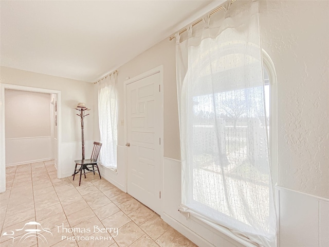 entryway with a textured wall and light tile patterned flooring