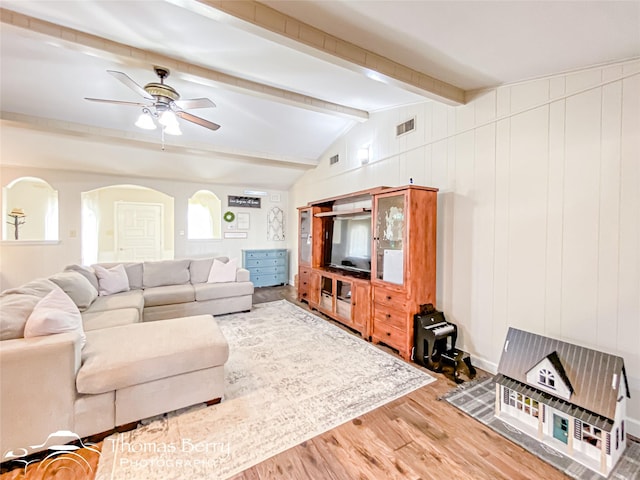 living area with lofted ceiling with beams, ceiling fan, arched walkways, wood finished floors, and visible vents