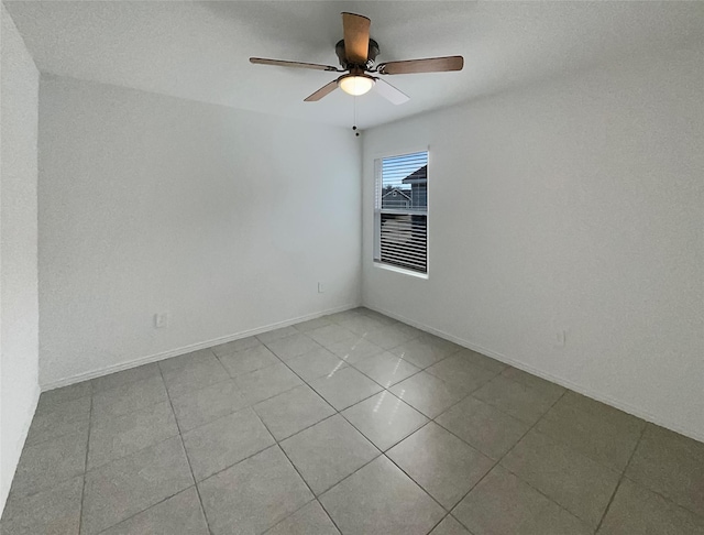 tiled spare room with baseboards and a ceiling fan