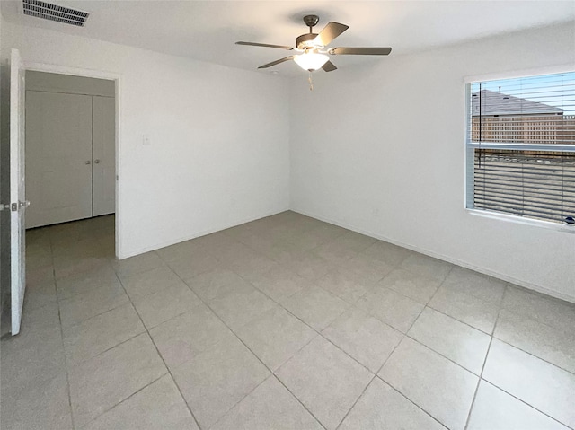 spare room featuring a ceiling fan, visible vents, and light tile patterned flooring