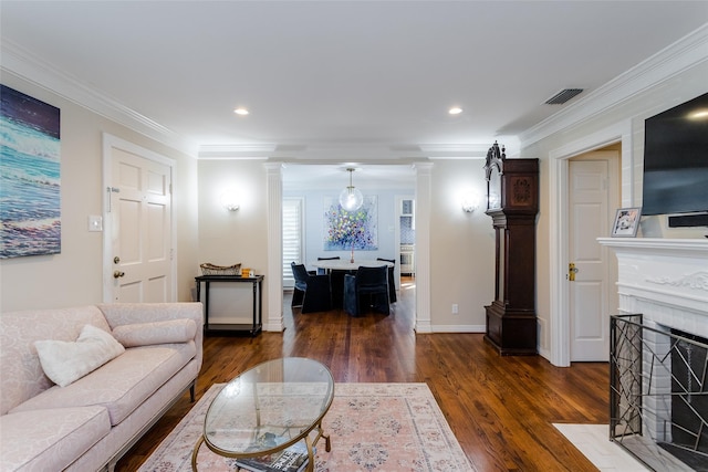 living area with a fireplace with flush hearth, visible vents, dark wood finished floors, decorative columns, and crown molding