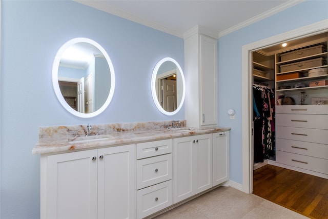 bathroom with double vanity, ornamental molding, a spacious closet, and a sink