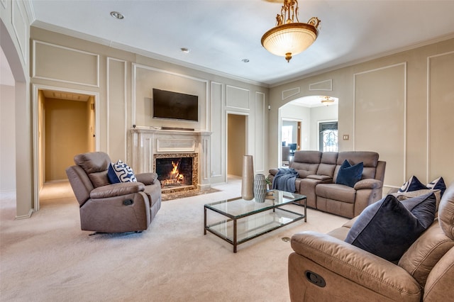 carpeted living room with a fireplace with flush hearth, arched walkways, a decorative wall, and crown molding