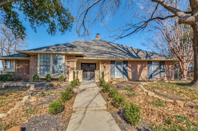 ranch-style home featuring a gate, a chimney, fence, and brick siding