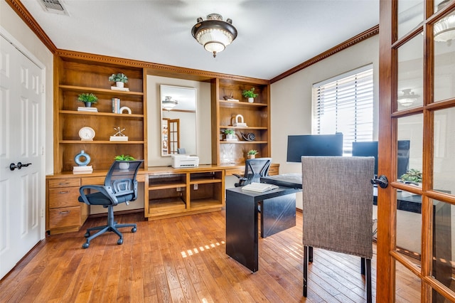 office with built in shelves, light wood-type flooring, visible vents, and crown molding