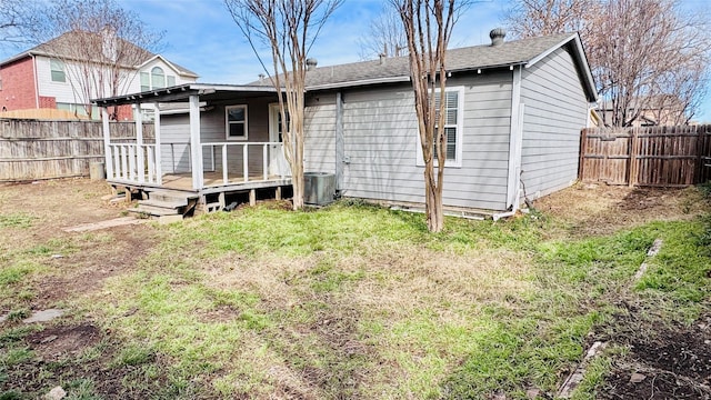 back of property featuring a fenced backyard, a lawn, a wooden deck, and central air condition unit