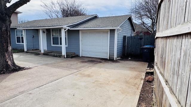 ranch-style home featuring an attached garage, driveway, fence, and a shingled roof