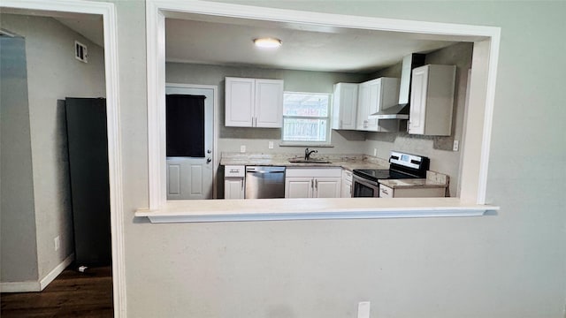 kitchen with a sink, white cabinetry, baseboards, appliances with stainless steel finishes, and wall chimney exhaust hood