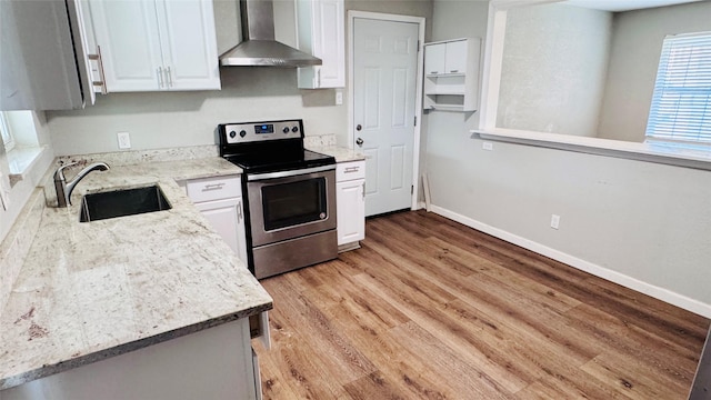 kitchen with baseboards, wall chimney exhaust hood, a sink, and electric stove