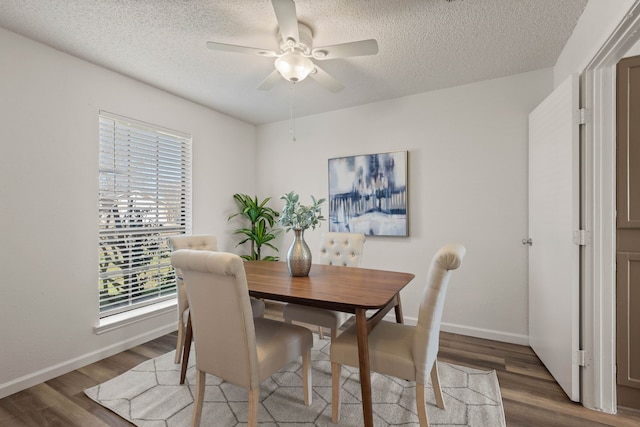 dining room with a textured ceiling, wood finished floors, a ceiling fan, and baseboards