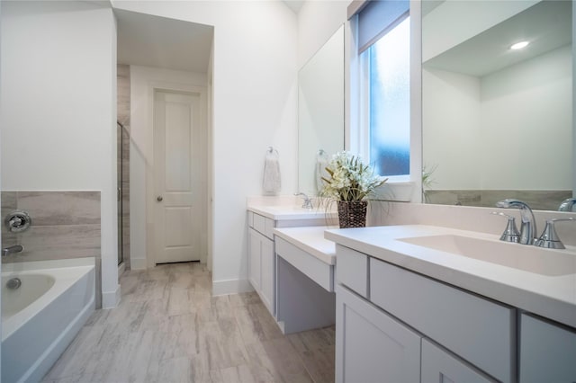 full bathroom featuring a garden tub, a shower stall, and vanity