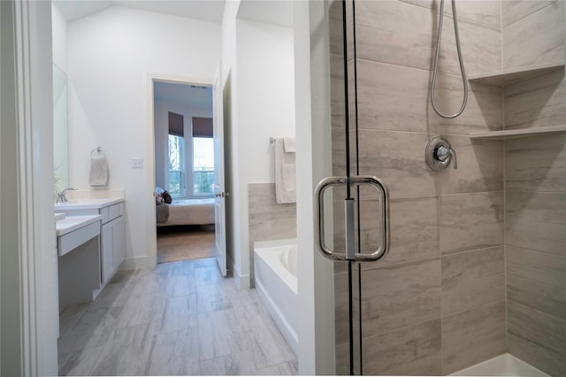 ensuite bathroom with ensuite bathroom, a garden tub, vanity, vaulted ceiling, and a stall shower