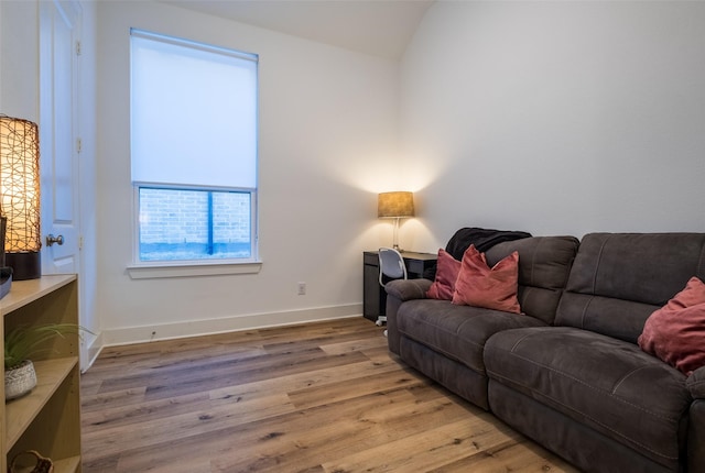 living room featuring light wood-style floors, baseboards, and vaulted ceiling