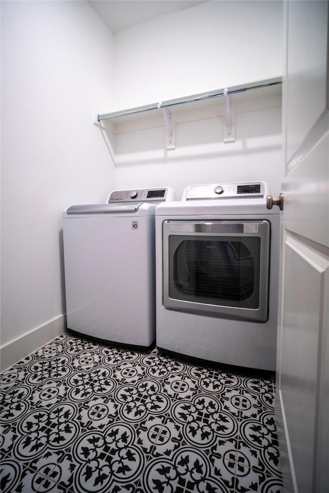 laundry room featuring tile patterned flooring, laundry area, washing machine and dryer, and baseboards