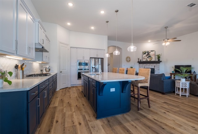 kitchen with visible vents, a breakfast bar area, stainless steel appliances, light wood-style floors, and a fireplace