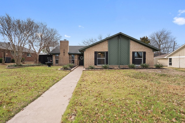 mid-century home featuring brick siding, a chimney, and a front lawn