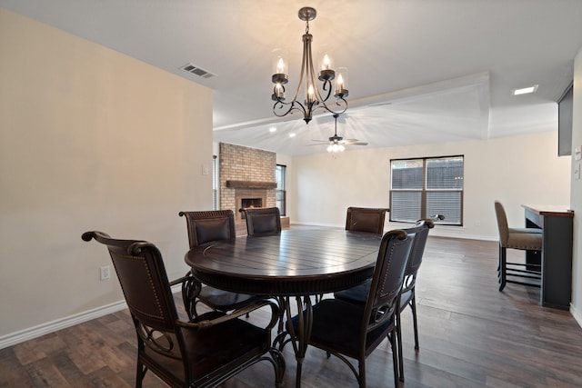 dining area featuring ceiling fan with notable chandelier, a fireplace, visible vents, baseboards, and dark wood-style floors