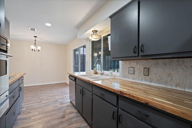 kitchen featuring light wood-style flooring, wood counters, a sink, visible vents, and stainless steel dishwasher