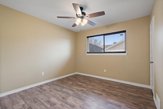 spare room with wood finished floors, a ceiling fan, and baseboards