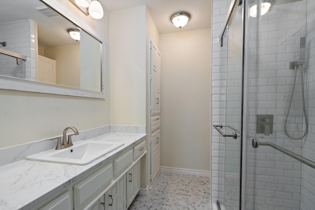 bathroom with baseboards, visible vents, a shower stall, and vanity