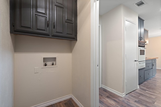 laundry room with washer hookup, cabinet space, visible vents, wood finished floors, and baseboards