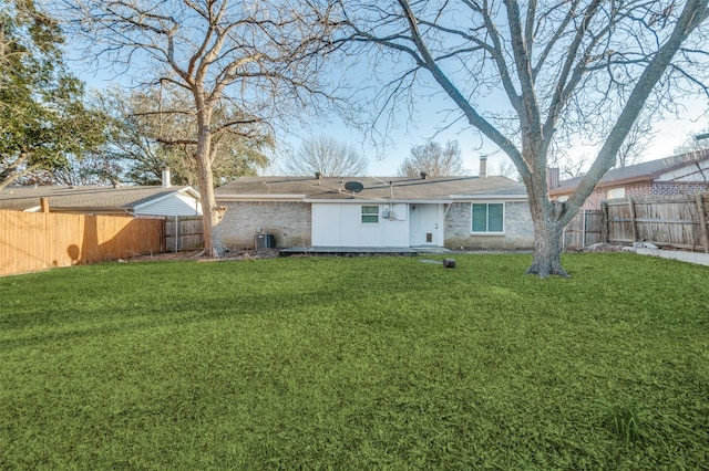 back of property with brick siding, a fenced backyard, cooling unit, and a yard