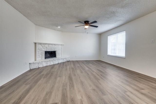 unfurnished living room featuring a fireplace, ceiling fan, a textured ceiling, wood finished floors, and baseboards