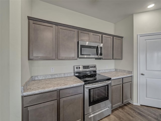 kitchen featuring dark wood-style floors, stainless steel appliances, recessed lighting, light countertops, and dark brown cabinets