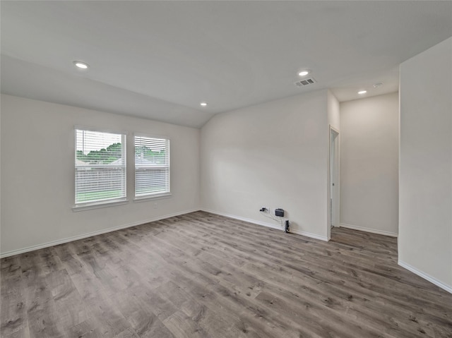 empty room featuring lofted ceiling, recessed lighting, wood finished floors, visible vents, and baseboards