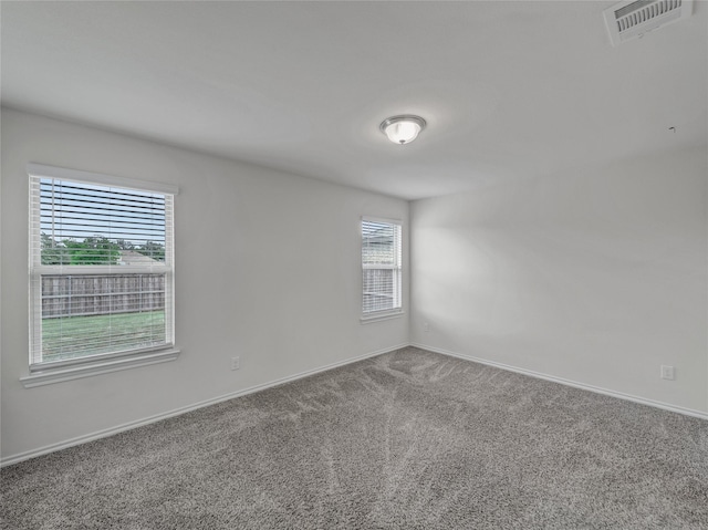 carpeted empty room featuring visible vents and baseboards